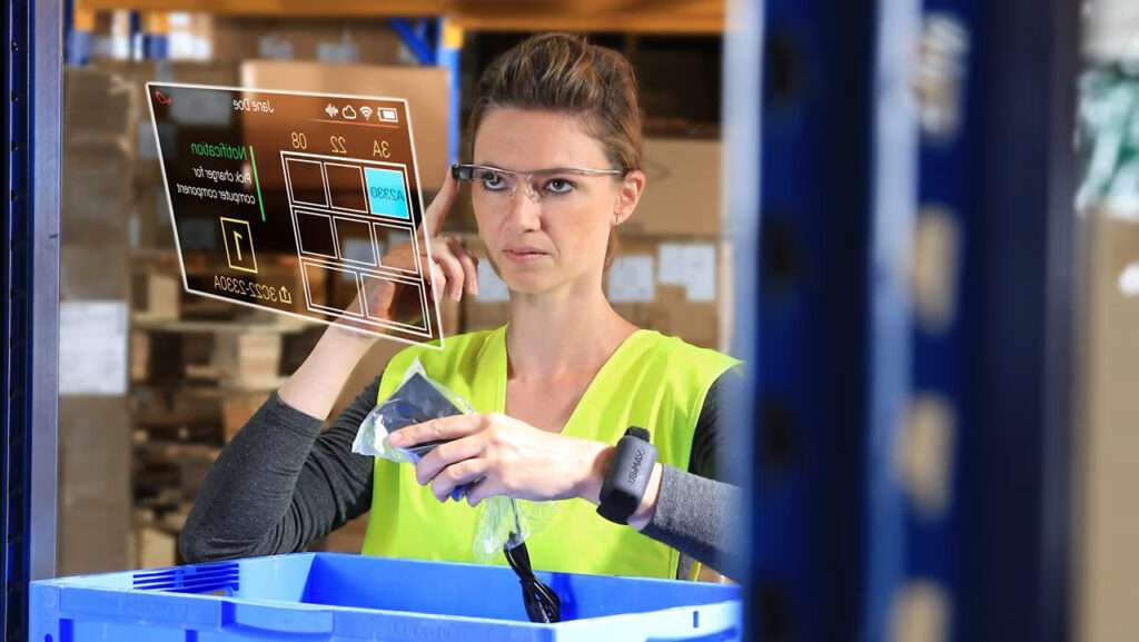 "Warehouse worker in a high-visibility vest using smart glasses to interact with an augmented reality inventory interface while sorting items into a blue bin, highlighting technology in logistics.
