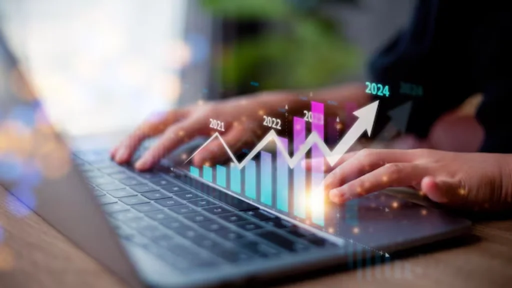 Hands typing on a laptop keyboard with a digital overlay of a rising graph showing yearly progress from 2021 to 2024, symbolizing business growth and digital transformation.